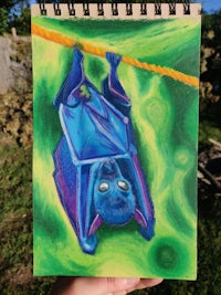 a person holding up a notebook with a drawing of a bat