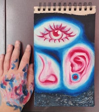 a person's hand with paint on it and a painting of an ear